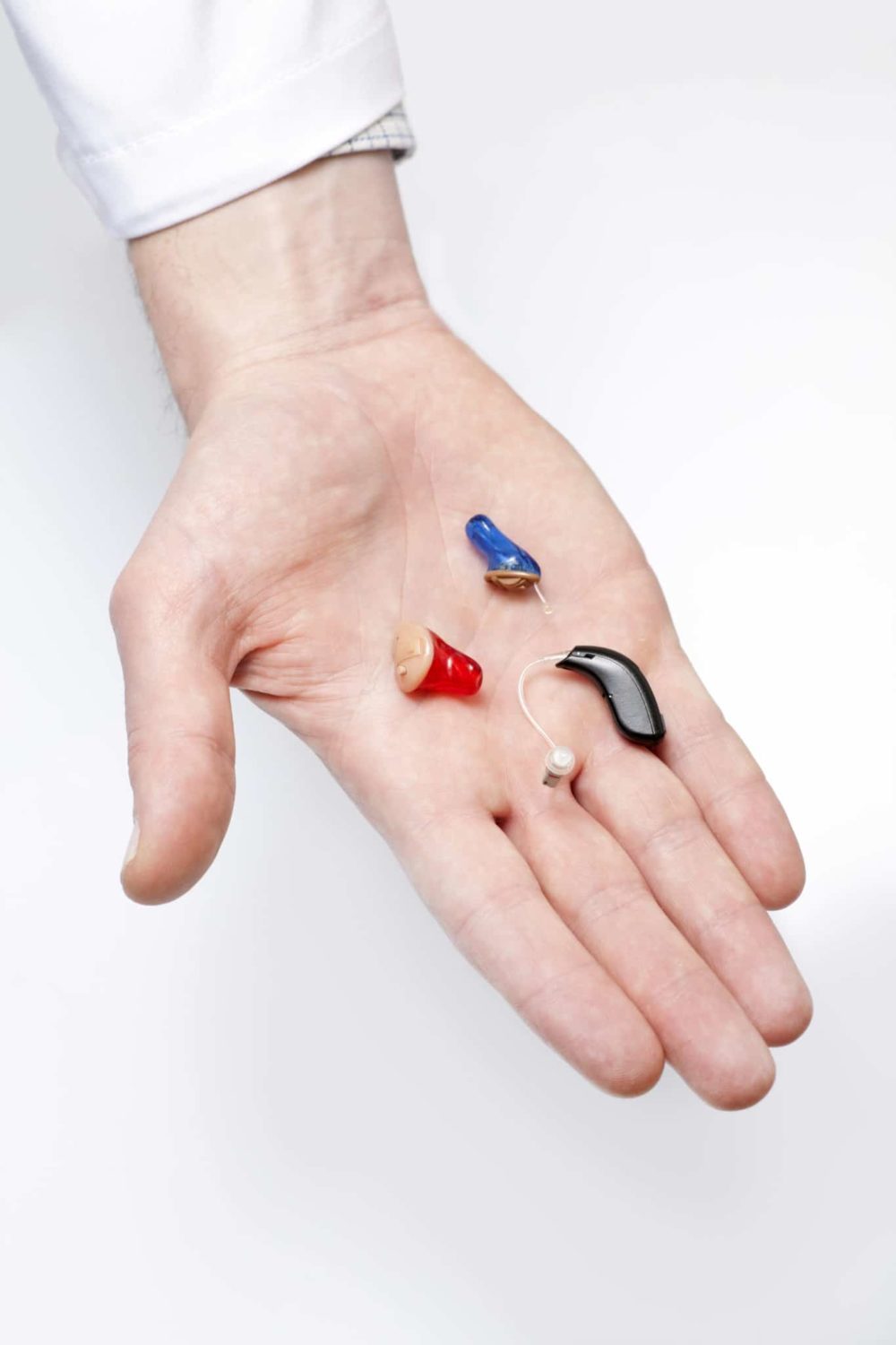 A hearing instrument specialist in Pennsylvania holding multiple hearing aids and hearing devices in their hand.