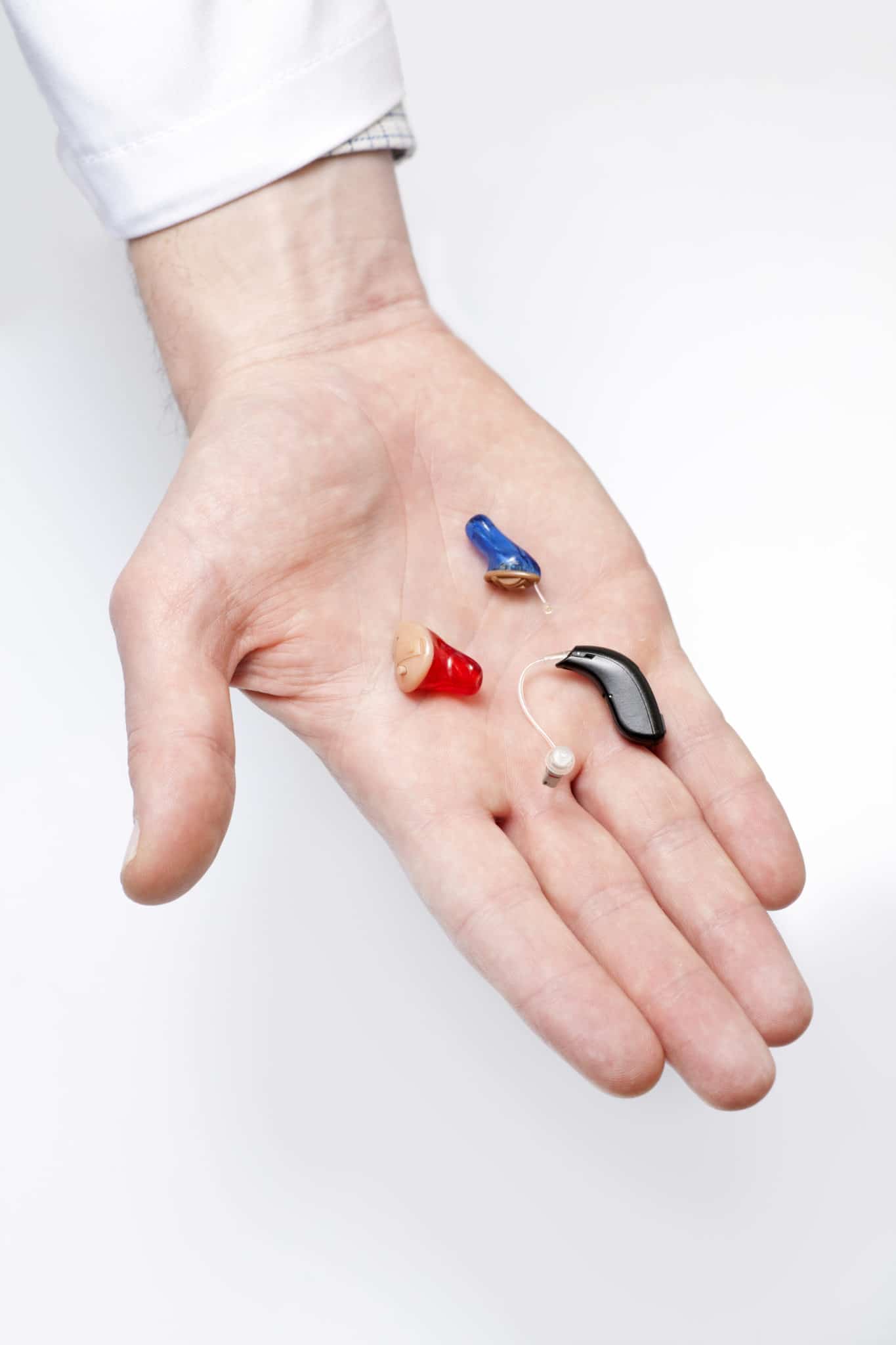 A hearing instrument specialist in Pennsylvania holding multiple hearing aids and hearing devices in their hand.
