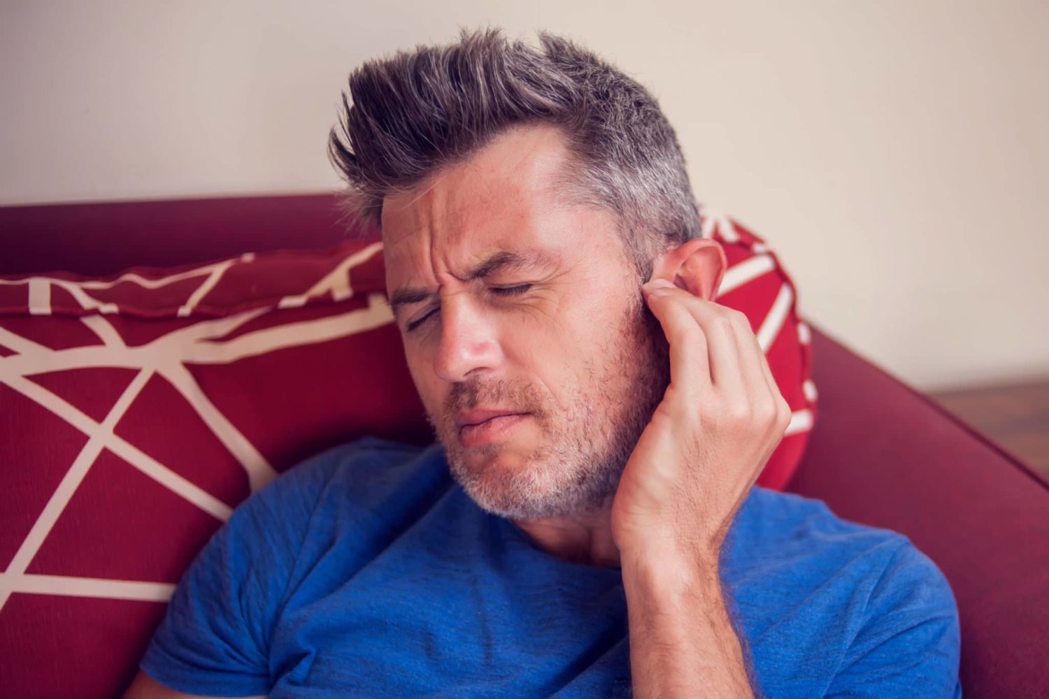 Experiencing tinnitus ear pain, a man put his hand to his ear for pain relief in Pennsylvania.