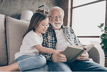 Older man and young child reading a novel about hearing health in their Pennsylvania home.