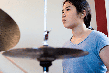 A drummer in Pennsylvania wearing hearing protection during her drum lessons to protect her hearing.